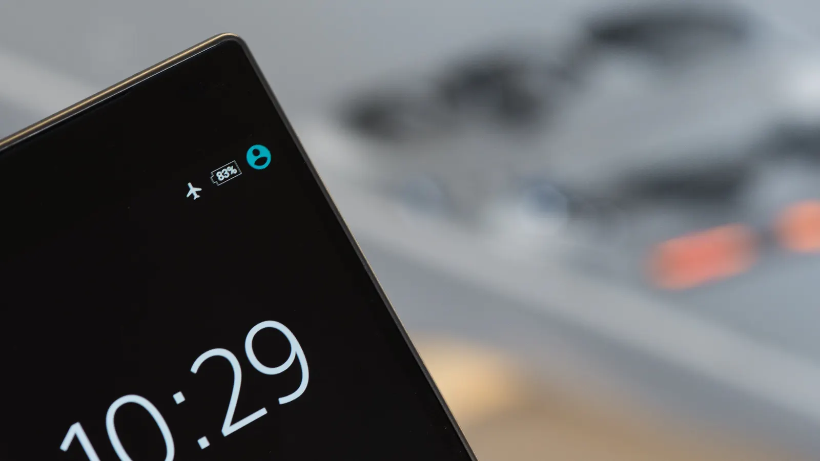 Coin d'un téléphone intelligent affichant l'heure sur un écran noir, fond flou