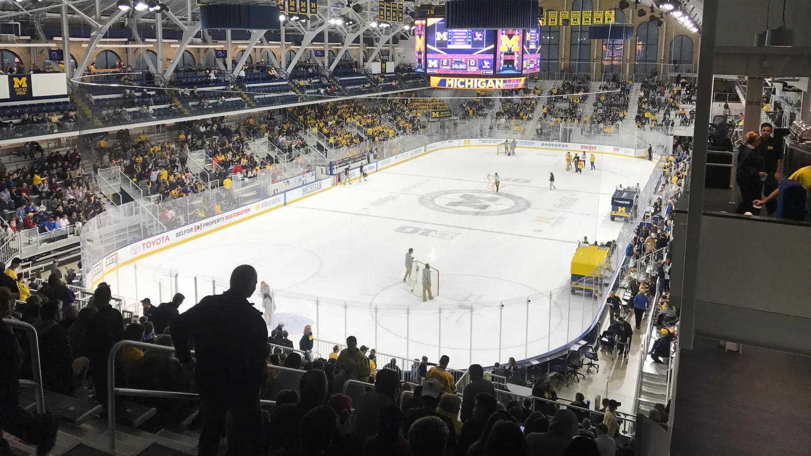 Intérieur d'une grande patinoire de hockey pendant l'entracte, avec la foule dans les gradins et un tableau indicateur
